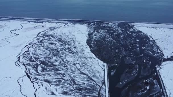 Zoom in drone view of breathtaking estuary of frozen river located on snowy shore of sea on winter day in Iceland - Footage, Video