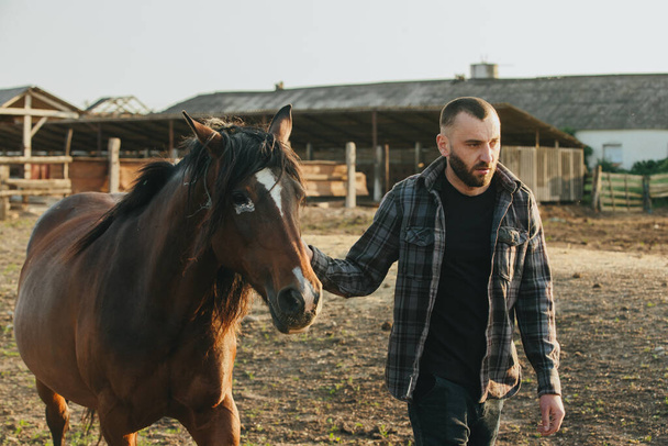 Молодий фермер працює в колоді з конями. Молодий чоловік піклується про коней на фермі. - Фото, зображення