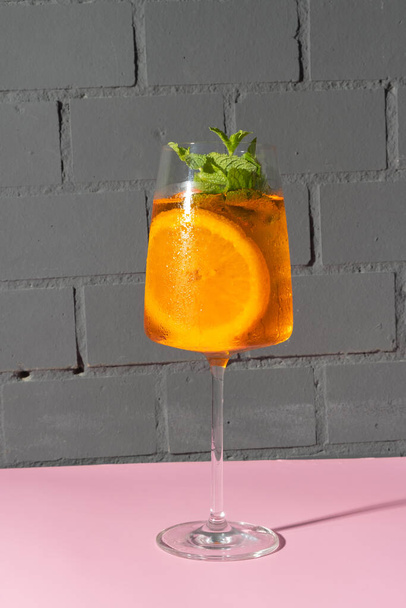 Pij kieliszki z koktajlem alkoholowym z pomarańczą i miętą. Relaks orzeźwiający napój w restauracji. - Zdjęcie, obraz