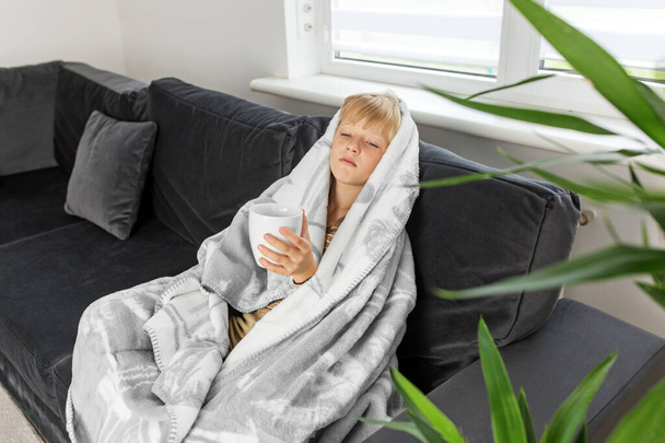 Niño preadolescente enfermo con fiebre alta y dolor de garganta y sentirse mal, sentado en casa en el sofá. Frío estacional. - Foto, Imagen