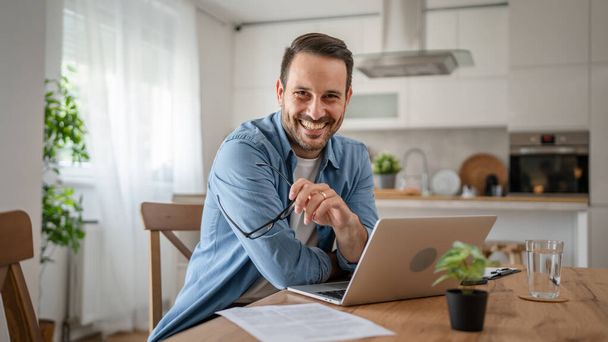 jeden mężczyzna dorosły biały mężczyzna z brody pracy na swoim laptopie w domu szczęśliwy uśmiech sukces wolny strzelec przedsiębiorca lub zdalnej pracy koncepcja - Zdjęcie, obraz