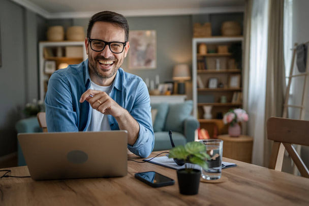 egy férfi felnőtt kaukázusi férfi szakállas munkát a laptop számítógép otthon boldog mosoly siker szabadúszó vállalkozó vagy távoli munka koncepció - Fotó, kép