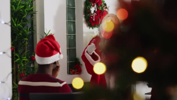 Gerente vestido como Santa Claus durante la temporada navideña celebrando reunión de equipo, presentando cartas de negocios en pantalla digital. Líder de equipo en oficina decorada festiva hablando con los miembros del personal - Metraje, vídeo