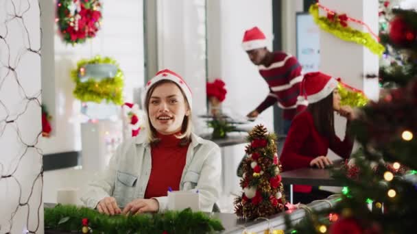 Porträt einer fröhlichen Frau im weihnachtlich dekorierten Büro, die an der Firma vlog für Marketing Social-Media-Kanal teilnimmt, Zuschauer begrüßt und lacht, Weihnachtsstimmung genießt - Filmmaterial, Video