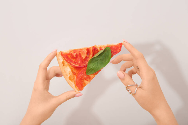 Woman holding slice of tasty pizza on grey background - Photo, Image
