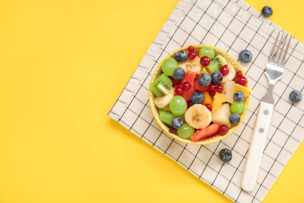 Schaal met verse fruitsalade op gele achtergrond - Foto, afbeelding