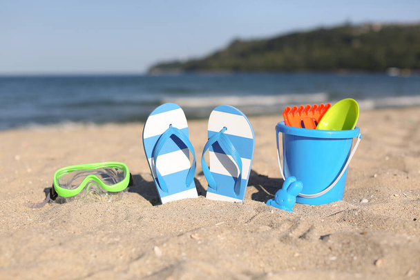 Stylische weibliche blaue Flip Flops, Schnorchelmaske und Strandaccessoires für Kinder auf Sand - Foto, Bild