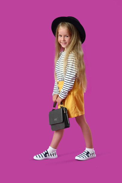 Linda niña con bolso sobre fondo púrpura - Foto, imagen