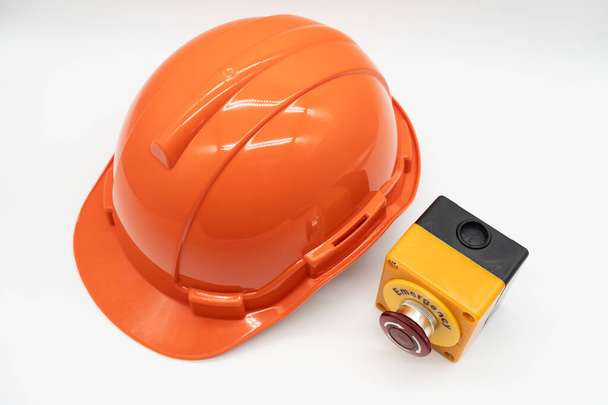 Orange safety hat with Emergency Stop Button isolated on white background. Safety First Concept. - Photo, Image