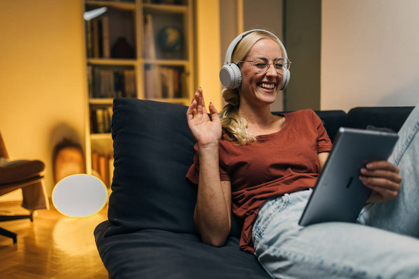 Cheerful woman is having a pleasant conversation during video call at home. - Foto, afbeelding