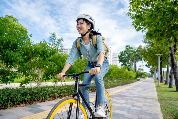 Şehir parkında bisiklet sürerken mutlu bir Asyalı kadın. O, ulaşım bisikletini kullanarak gülümsedi. Çevre dostu kavram. - Fotoğraf, Görsel