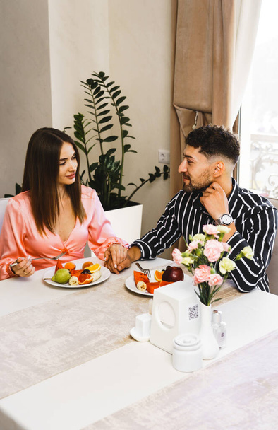 Ένα ερωτευμένο ζευγάρι τρώει πρωινό σε εστιατόριο σε ξενοδοχείο. Η έννοια των διακοπών σε ένα ξενοδοχείο - Φωτογραφία, εικόνα