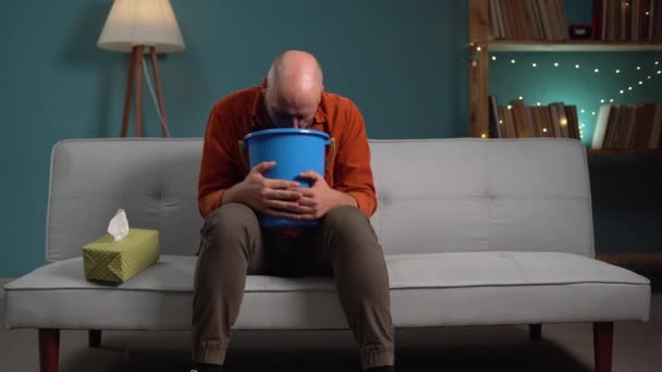 Концепция пищевого отравления. Мужчина, страдающий тошнотой и рвотой на диване дома. Копирование пространства - Кадры, видео