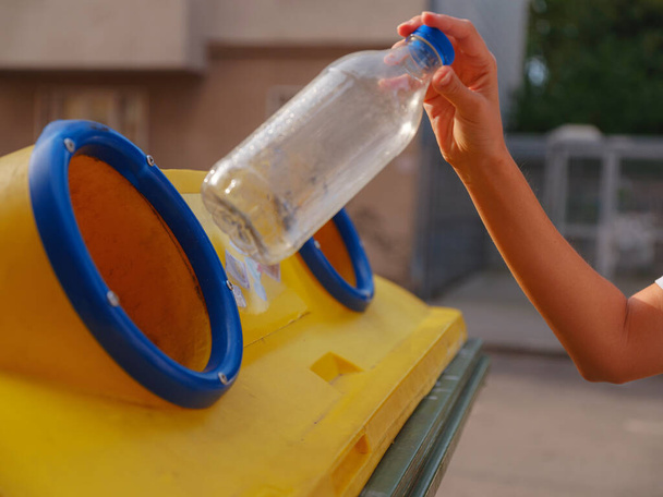 γυναίκα ρίχνουν πλαστικό μπουκάλι Ανακύκλωση περίπτερο κάδο στην ευρωπαϊκή οδό. Απορρίμματα διαχωρισμός σκουπίδια πριν από την πτώση σε κάδο απορριμμάτων για να σώσει τον κόσμο, φροντίδα του περιβάλλοντος. Σχέδιο διαχείρισης ανακύκλωσης απορριμμάτων ρύπανσης - Φωτογραφία, εικόνα