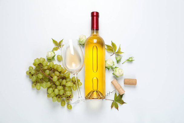 Botella de vino, uvas, rosas y vidrio sobre fondo blanco, vista superior - Foto, imagen