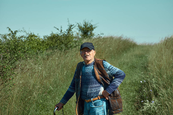 Vanha ukrainalainen mies kepin kanssa Länsi-Ukrainan vuorilla. Silmälasipäinen paimen ja turkki katsovat kameraan. Isoisän muotokuva. - Valokuva, kuva
