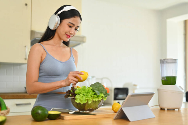 Красивая молодая женщина готовит свежий здоровый веганский салат на кухне дома. Диета и концепция здорового образа жизни. - Фото, изображение