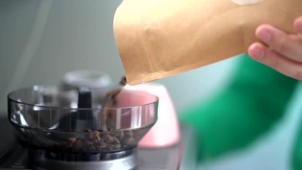 Περικοπή αγνώριστος πρόσωπο με χάρτινο πακέτο πλήρωση ηλεκτρικό μύλο με ψητά φασόλια καφέ στο σπίτι - Πλάνα, βίντεο