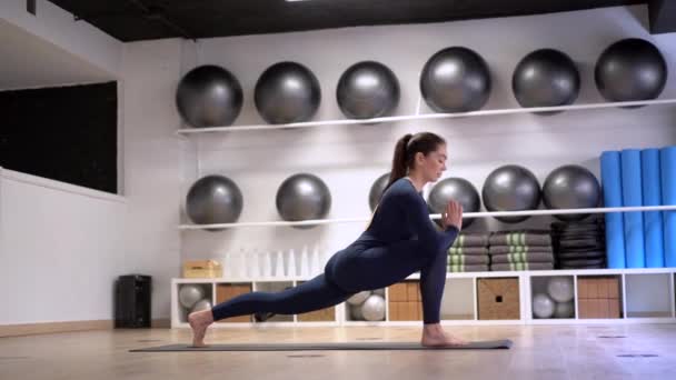 Hermosa mujer joven haciendo ejercicio en el interior, haciendo ejercicio de yoga en la habitación
 - Metraje, vídeo