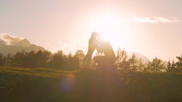 SILHOUETTE, LENS FLARE: Gelukkige hond met kwispelende staart en zijn eigenaar in gouden licht. Hart smeltende moment tussen jonge vrouw en haar hondje op de top van een schilderachtige berg in prachtige herfst zonlicht. - Video