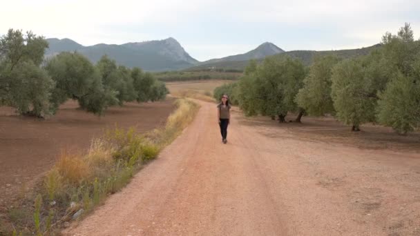 Vista frontal de cuerpo completo de viajera asiática caminando mientras está de pie en la plantación con exuberantes olivos verdes - Metraje, vídeo