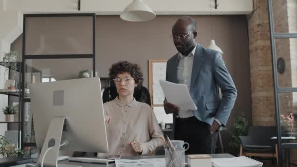 Mediana toma de afroamericanos hombres y mujeres trabajadoras de oficina caucásicas mirando la pantalla y discutiendo temas de trabajo - Imágenes, Vídeo