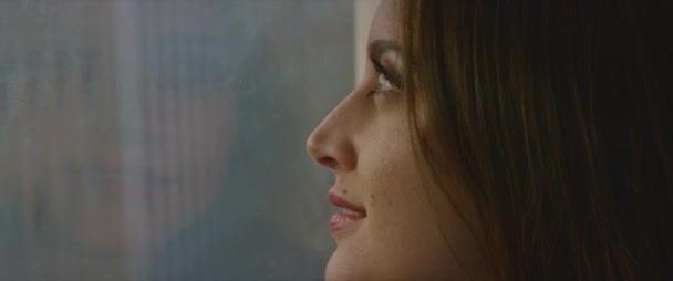 Lähikuva nuori kaunis nainen katselee ulos ikkunasta - Materiaali, video
