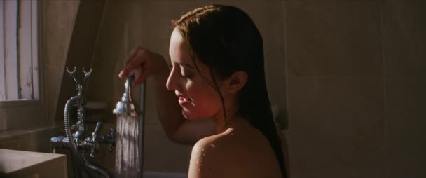 Jonge ontspannen vrouw genieten van een warme douche in een bad thuis - Video