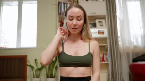 Αθλητική γυναίκα σε activewear κοιτάζοντας κάμερα, ενώ μιλώντας στο φως σαλόνι κατά τη διάρκεια της κατάρτισης - Πλάνα, βίντεο