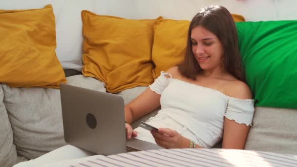 Delighted vrouw zitten op de bank met laptop en het maken van de aankoop met plastic kaart tijdens online winkelen in de achtertuin tent - Video