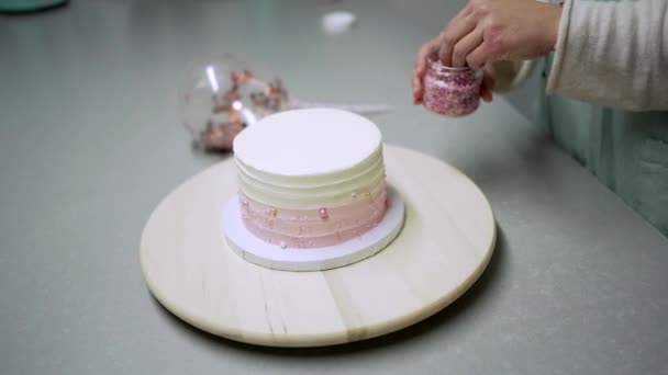 Crop anonieme vrouwelijke banketbakker regelen eetbare parels op taart bedekt met room tijdens het werken aan de balie in zoetwaren - Video