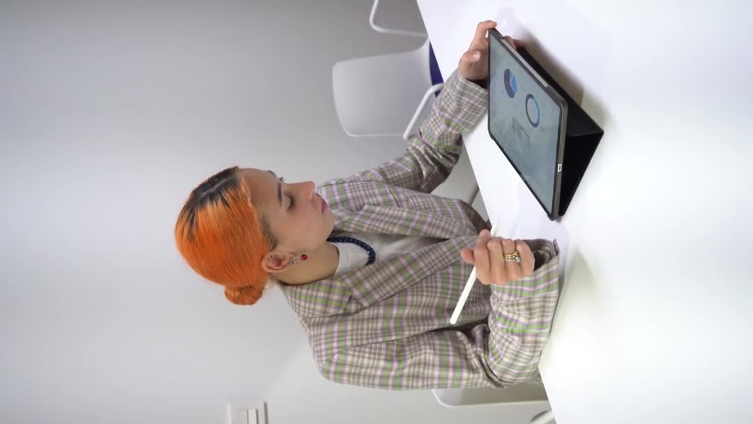 Concentrated female employee using tablet while sitting at table and working in coworking space - Footage, Video