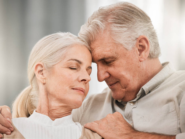 Old couple, hug and forehead touch, relax on sofa with love and support, bonding while at home with trust and comfort. People together in marriage, partner and retirement with calm and peace of mind. - Photo, Image