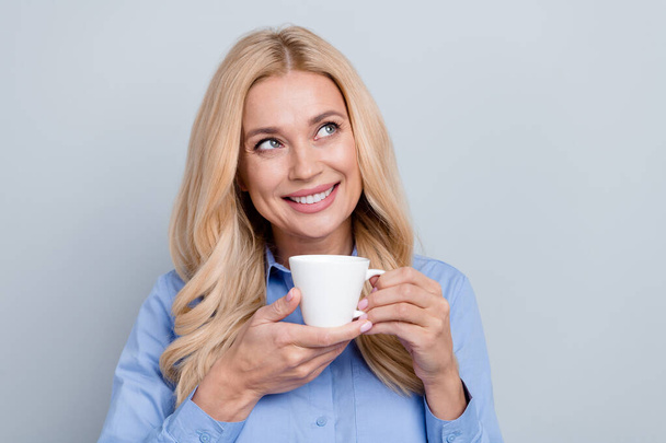 Fotografie krásné elegantní dáma zubatý úsměv ruce držet čerstvý šálek kávy vypadat prázdný prostor izolované na šedém pozadí. - Fotografie, Obrázek