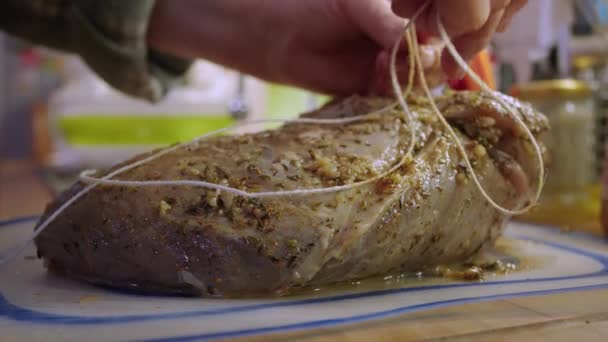 Housewife tying up marinated piece of raw veal for roasting - Séquence, vidéo