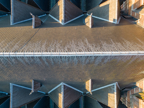 Deze betoverende luchtfoto biedt een abstract perspectief op de ingewikkelde patronen en details die het dak van een pittoreske kerk sieren. De geometrische symmetrie en architectonische elegantie creëren een - Foto, afbeelding