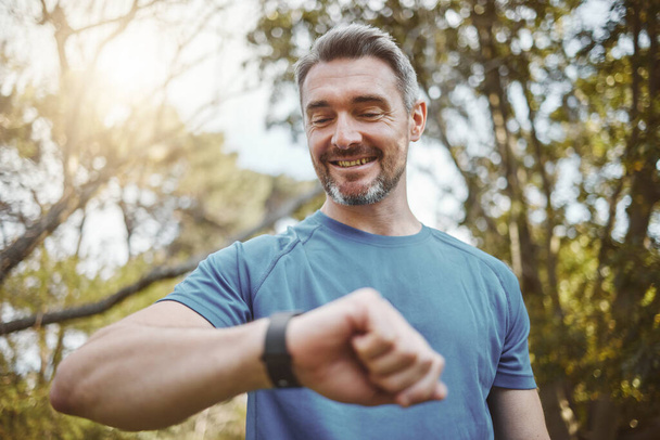 Happy runner man, smart watch and park for check, smile or reading for time, results or fitness in nature. Person, iot clock and monitor for speed, heart rate or smile for exercise, workout or health. - Photo, Image