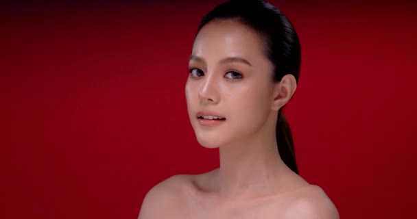 Mooie jonge aziatische vrouw met schone frisse huid op rode achtergrond, Gezichtsverzorging, Gezichtsbehandeling, Cosmetologie, schoonheid en spa, Aziatische vrouwen portret. - Video
