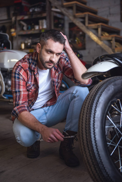 Yakışıklı adam bir motosiklet tamircisi onarıyor - Fotoğraf, Görsel