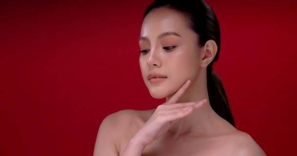 Mooie jonge aziatische vrouw met schone frisse huid op rode achtergrond, Gezichtsverzorging, Gezichtsbehandeling, Cosmetologie, schoonheid en spa, Aziatische vrouwen portret. - Video
