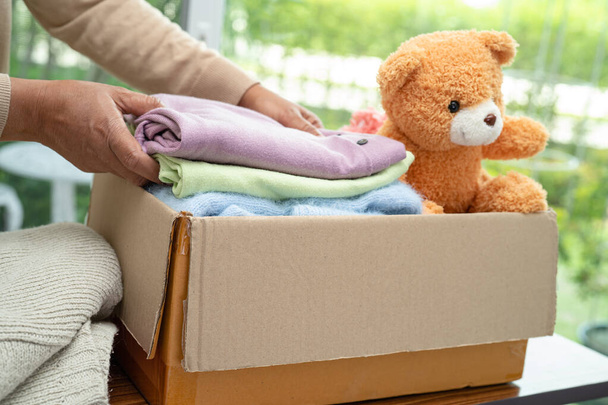 Boîte de dons avec vêtements usagés et poupée à la maison pour soutenir l'aide aux pauvres dans le monde. - Photo, image