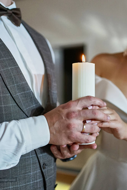 Η νύφη και ο γαμπρός κρατούν αναμμένο κερί. Η τελετή μετακόμισης της οικογενειακής εστίας. Εθνικές παραδόσεις.                               - Φωτογραφία, εικόνα