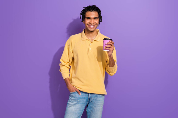 Photo of positive friendly man wear trendy yellow clothes hand plastic cup drink tasty coffee isolated on purple color background. - Foto, imagen