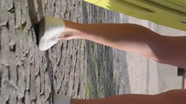 Super-Zeitlupe einer Frau mit Reisekoffer vor dem Hintergrund von Sonnenstrahlen. Natürliches Sonnenlicht im Rahmen. Vertikales Video. - Filmmaterial, Video