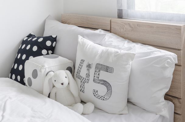 black and white pillows with doll on wooden bed in kid's bedroom - Photo, Image