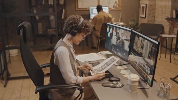 Full shot fena běloška producent při pohledu na dvě obrazovky porovnávání záběrů s projektem storyboard v kanceláři ve večerních hodinách - Záběry, video