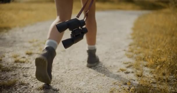 Bassa sezione di donna con binocolo che cammina sulla passerella nella foresta durante le vacanze - Filmati, video