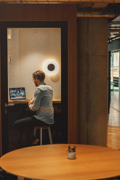 Empresario tienen videoconferencia con colega mientras está sentado en coworking acogedor. Foto de alta calidad - Foto, Imagen