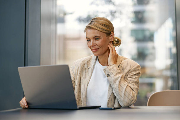 Responsabile vendite donna che lavora su laptop mentre si siede alla scrivania in coworking moderno  - Foto, immagini