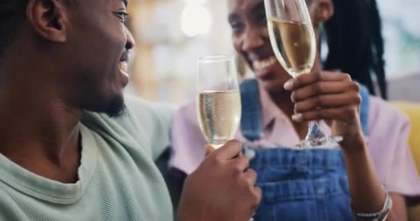 Czarna para, tosty i szampan w domu, szczęśliwy lub wiążący się w salonie. Afrykański mężczyzna, kobieta i wino okrzyki, pić szklankę lub alkohol, uśmiech lub rocznica świętowania, relaks i miłość razem. - Materiał filmowy, wideo